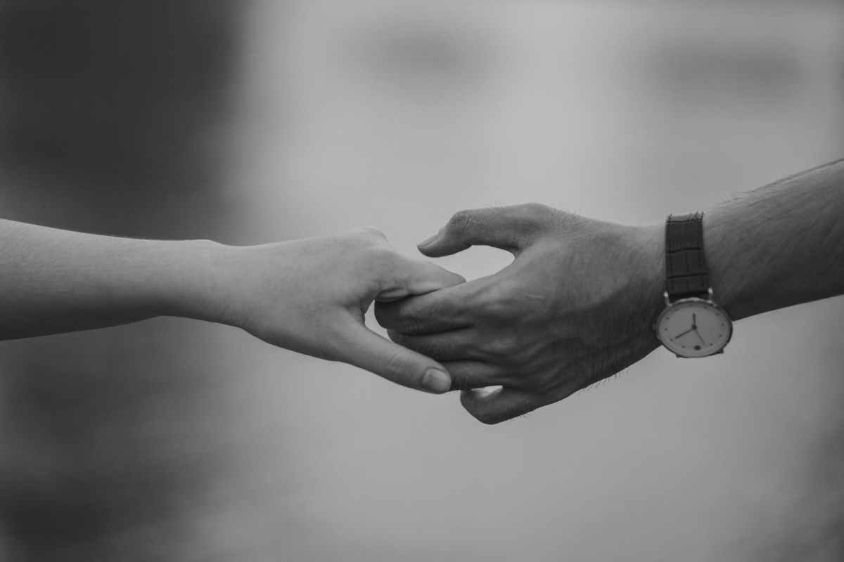monochrome photo of couple holding hands